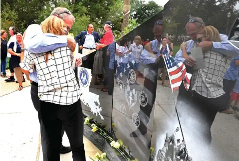  ?? Patrick Dennis photos/The Advocate via AP ?? ■ David Ruth, left, and Jessica Fugitt embrace at a monument for families of fallen service members following a dedication ceremony Sunday in Baton Rouge. Fugitt was engaged to Navy pilot Lt. Patrick Ruth when he was killed in a training accident one year ago. David Ruth is the Navy pilot’s father.