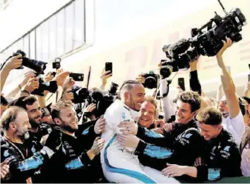 ?? GETTY ?? Der Weltmeiste­r und seine Zuarbeiter: Lewis Hamilton lässt sich von der Mercedes-Crew feiern.
