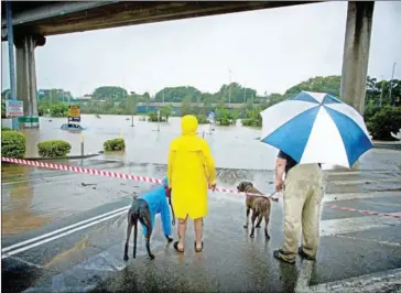  ?? PATRICK HAMILTON/AFP ?? People look at submerged cars in a flooded carpark in Toombul, in Queensland, yesterday. Torrential rain is hampering relief efforts following powerful Cyclone Debbie.