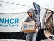  ?? DELIL SOULEIMAN/GETTY-AFP ?? A Syrian boy carries a humanitari­an aid relief box Wednesday at a refugee camp in al-Hawl, about 9 miles from Iraq.