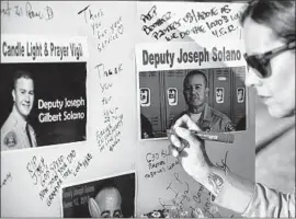  ?? Robert Gauthier Los Angeles Times ?? DEPUTY Cynthia Balderrama signs a memory board Thursday at a vigil for Solano. Relatives called him “J.C.,” short for “Joe Cool,” because he was so poised.