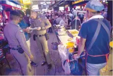  ?? — AFP ?? Police inspecting the passport of a foreigner in Bangkok’s Patpong district during an operation ‘X-ray Outlaw Foreigner’.