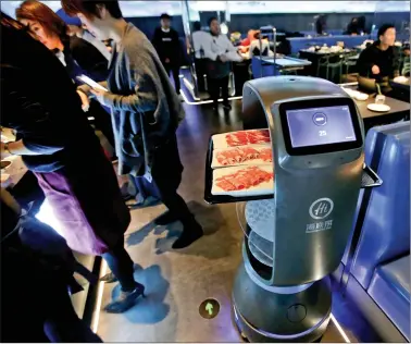  ?? REUTERS ?? A robot server delivers dishes to fulfill orders from diners at Haidilao’s new artificial intelligen­ce hotpot restaurant in Beijing, Chinaon Wednesday.