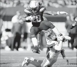  ?? Gregory Shamus Getty Images ?? MELVIN GORDON, leaping over Cleveland’s Denzel Ward, suffered a hamstring injury Friday and missed the Chargers game against Tennessee.