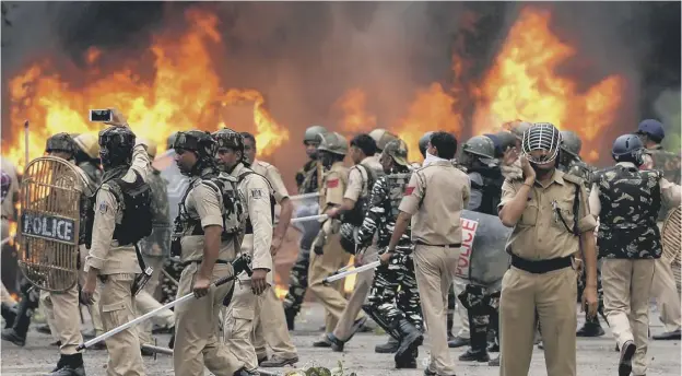  ?? PICTURE: GETTY IMAGES ?? Indian security forces in Panchkula with burning vehicles set alight by rioting followers of Ram Rahim Singh after he was convicted of rape