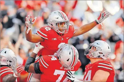  ?? [ADAM CAIRNS/DISPATCH PHOTOS] ?? Ohio State running back J.K. Dobbins gets a lift from tackle Jamarco Jones with center Billy Price looking on after Dobbins broke a 52-yard touchdown run during the third quarter.