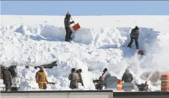  ?? Paul Bilodeau / Associated Press ?? Workers remove snow from a high school gym Friday as the Boston area braced for more.