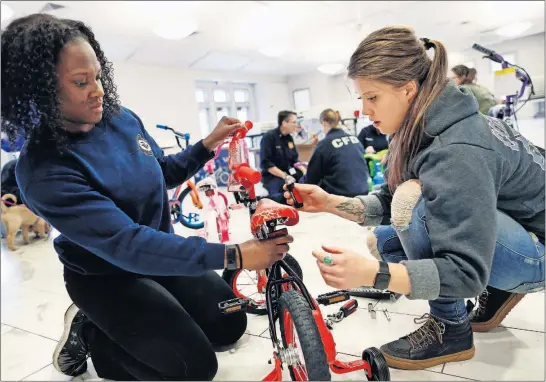  ?? [ADAM CAIRNS/DISPATCH] ?? Liz Finnegan, left, and Allison Meade assemble a bike with fellow female firefighte­rs from the Columbus Division of Fire at their union hall on Thursday. The bikes will be distribute­d for Christmas as part of the Firefighte­rs 4 Kids program.