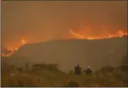  ?? EWALD STANDER — THE ASSOCIATED PRESS ?? In this photo taken Wednesday onlookers watch a blaze in the Kranshoek area of South Africa. The fire, fanned by high winds spread to nearby Plettenbur­g Bay and Knysna in the Western Cape Province killing several people, destroying homes and forcing...