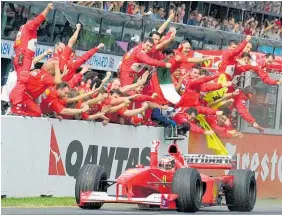  ?? Photo / AP ?? Ferrari’s Michael Schumacher is cheered on by his pit crew as he heads for the finish of the Australian Grand Prix in 2000.