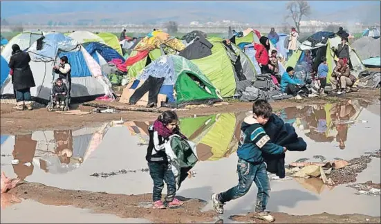  ?? LOUISA GOULIAMAKI / AFP ?? Dos niños acarrean mantas en el campamento de Idomeni, donde miles de refugiados esperan para pasar de Grecia a Macedonia