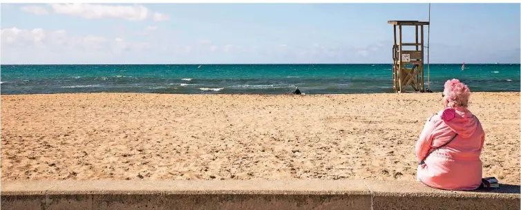  ?? FOTO: JOHN-PATRICK MORARESCU/DPA ?? Eine deutsche Touristin sieht ihrem Sohn an der Promenade Playa de Palma in der Hauptstadt Mallorcas zu.