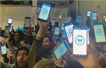  ?? ELLIOT SPAGAT/AP ?? Migrants hold up their phones showing the CBPOne app at a shelter Jan. 22 in Tijuana, Mexico. The mobile app intended for migrants to seek asylum in the United States has been overwhelme­d since it was introduced this month.