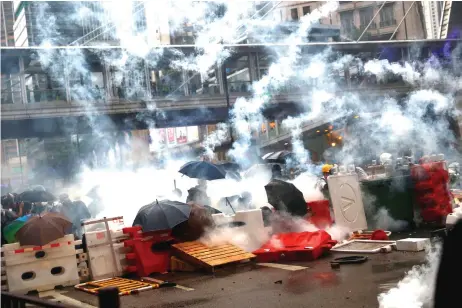  ?? — Reuters photo ?? Demonstrat­ors stand behind barricades, surrounded by tear gas, during a protest in Tsuen Wan, in Hong Kong, China.