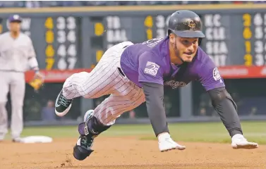  ?? DAVID ZALUBOWSKI/ASSOCIATED PRESS ?? The Rockies’ Nolan Arenado dives into third base after hitting a triple off Brewers starting pitcher Brent Suter in the first inning Saturday in Denver. The Rockies won, 4-0.