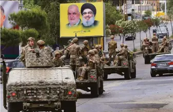  ?? Mohammed Zaatari / Associated Press ?? The Lebanese army patrols past a banner with the head of Hezbollah’s parliament­ary bloc, Mohammed Raad Hezbollah (left) and leader Said Hassan Nasrallah in Nabatiyeh, Lebanon.