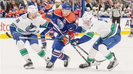  ?? Jason Franson/Associated Press ?? Vancouver Canucks’ Christian Wolanin (86) and James Hamblin (57) works for the puck against Edmonton Oilers’ Connor McDavid (97) during the second period a preseason game Wednesday in Edmonton, Alberta.