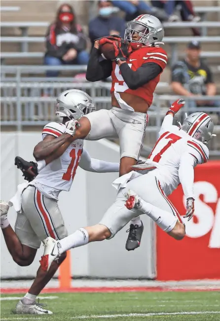  ?? ADAM CAIRNS/COLUMBUS DISPATCH ?? Wide receiver Garrett Wilson catches a pass over safety Bryson Shaw (17) and cornerback Ryan Watts during the Ohio State spring football game on Saturday.