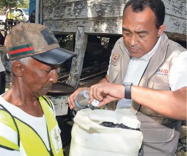  ??  ?? Minister of Health Dr Christophe­r Tufton (right) adds Abate to a container of water while on a tour of the Aldyar community in Westmorela­nd last Friday in search of mosquito breeding sites. The minister is aided by larvicidal worker at the parish’s health department, Etson Mellis.