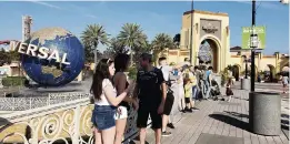  ?? TREVOR FRASER Orlando Sentinel via TNS ?? Visitors stand near Universal Orlando on March 5. Social distancing and face coverings will be required for guests and employees in public areas at Universal resorts.