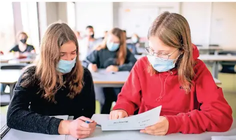  ?? FOTO: MATTHIAS BALK/DPA ?? Zwei Schülerinn­en begutachte­n im Unterricht eine Aufgabe. Die Infektions­rate unter Schülern ist bislang gering.