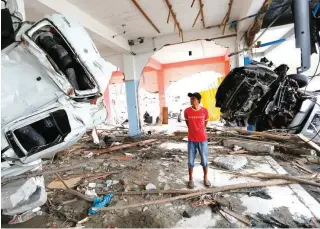  ??  ?? A man inspects the wreckage of vehicles inside a building at the tsunamirav­aged area in Palu, Central Sulawesi, Indonesia, Thursday, Oct. 11, 2018. A 7.5-magnitude earthquake rocked Central Sulawesi province on Sept. 28, triggering a tsunami and mudslides that killed a large number of people and displaced tens of thousands of others. (AP Photo/Dita Alangkara)