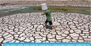  ?? ?? A man carries a plastic bucket across the cracked bed of a dried-up pond in Vietnam’s southern Ben Tre province on March 19, 2024. — AFP