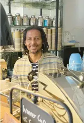  ?? ALMAZ ABEDJE/AP ?? Anteneh Mulu, 46, stands Aug. 31 behind the counter of his coffee shop, the Ethiopian Coffee Company in central London, after serving a customer.
