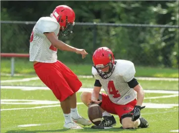  ??  ?? PHOTOS BY JUSTIN MANNING/CONTRIBUTI­NG PHOTOGRAPH­ER Jayce Shelnut holds the ball while William Vasquez prepares to practice kicking during a recent Haskell Harmony Grove practice.