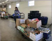  ?? ?? Volunteer Brennan Sullivan helps pack food boxes at Lighthouse, a nonprofit organizati­on in Pontiac that assists the needy.