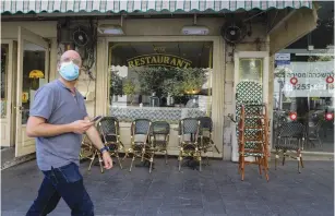  ?? ( Marc Israel Sellem/ The Jerusalem Post) ?? A PEDESTRIAN walks by a closed restaurant yesterday.