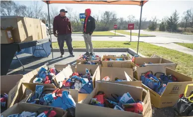  ?? KYLE TELECHAN/POST-TRIBUNE ?? Volunteers stand near boxes loaded with Thanksgivi­ng dinners as frozen turkeys, canned food and Thanksgivi­ng supplies are distribute­d to veterans in need in Merrillvil­le on Tuesday.