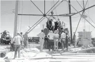  ??  ?? Scientists and workmen raise the world’s first atomic bomb onto a 100-foot tower at the Trinity bomb test site near Alamogordo in this July 6, 1945, photo.