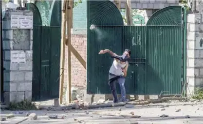  ?? — AP ?? SRINAGAR: A masked Kashmiri student protestor throws stones at Indian policemen in Srinagar, Kashmir.