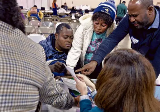  ?? JOSH REYNOLDS FOR THE BOSTON GLOBE ?? Jean Fedner Estesma and Guerline Saul (center) got help applying for work permits during a clinic in Reading last month.