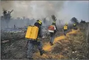  ?? Edmar Barros Associated Press ?? FIRE CREWS head to a burned area in Apui in Amazonas state of northweste­rn Brazil last month.