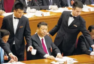  ?? THE ASSOCIATED PRESS ?? Chinese President Xi Jinping, center, sits as attendants refill drinking mugs for tea during a plenary session of China’s National People’s Congress at the Great Hall of the People in Beijing on Friday.