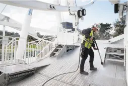  ??  ?? Daniel Hunter washes the deck of the SkyStar ride in March. It was originally to open in April as part of the park’s anniversar­y celebratio­n.