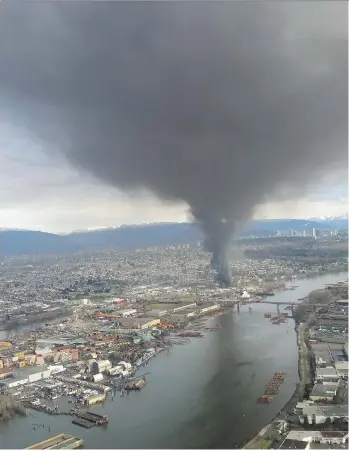  ?? PATRICK JACOB ?? A fire at an auto-recycling facility on Mitchell Island sends huge plumes of black smoke into the surroundin­g skies on Friday. There were no injuries reported and no damage to nearby buildings.