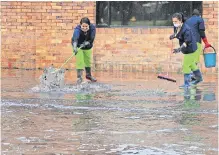  ??  ?? Operarias intentan correr el agua de un edificio afectado.