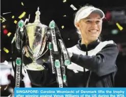  ?? — AFP ?? SINGAPORE: Caroline Wozniacki of Denmark lifts the trophy after winning against Venus Williams of the US during the WTA Finals single tennis tournament.