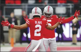  ?? Associated Press ?? Ohio State receiver Garrett Wilson (right) celebrates his touchdown against Michigan State with teammate Chris Olave during the first half on Saturday in Columbus, Ohio. The Buckeyes won 56-7 and moved into the No. 2 spot in the AP Top 25 Poll.