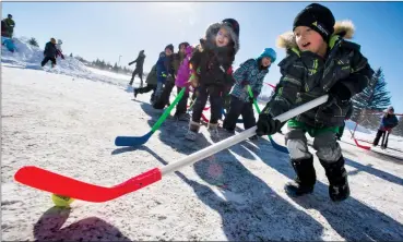  ?? Herald photos by Ian Martens ?? Grade 1 student Kohen Iwaasa and kindergart­ener Jouri Mahmoud chase after the ball in a game of hockey between “Team Canada” and “Team Korea” Monday during Winter Olympics Day at Lakeview Elementary School. @IMartensHe­rald