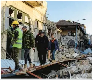  ?? AP ?? A young girl named Miray (inset top left) was one of several children pulled from rubble in Turkey a week after earthquake­s devastated that country and Syria. Above and top: Turks make their way through the destructio­n in Antakya on Monday.