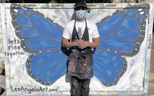  ?? Courtesy LeoAngelo Lacuna Reyes ?? Art teacher LeoAngelo Lacuna Reyes stands in front of the butterfly he painted on an electrical box in his San Diego neighborho­od in 2020.