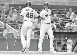  ?? ERIC ESPADA/GETTY ?? Cesar Puello, left, is congratula­ted by Miami Marlins teammate Garrett Cooper after scoring in the second inning against the San Diego Padres on Thursday at Marlins Park.