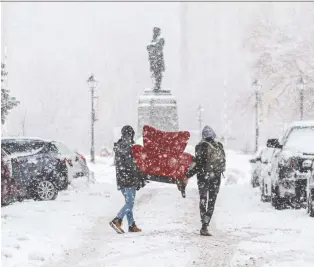  ?? DAVE SIDAWAY ?? Montrealer­s woke up to a snowy morning on Saturday. The statue of John Young looks on as brothers Alex and Max Fontaine, left to right, carry a chair into their apartment on Saint-pierre Street in Old Montreal.