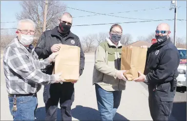  ?? LYNN KUTTER ENTERPRISE-LEADER ?? Preston Beeks, left, pastor of Main Street Baptist Church, and Dee Harper, pastor of Farmington United Methodist Church, hand over BBQ meals to Farmington police officers Jimmy Brotherton and Dylan Crutchfiel­d. LIFE Ministries and Farmington churches recently provided a free lunch to first responders, city workers, postal workers and doctor and dental offices.