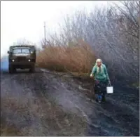  ?? ?? An elderly woman carrying a bucket walks along the road near Bakhmut, on Sunday, amid the Russian invasion of Ukraine.