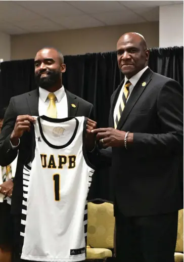  ?? (Pine Bluff Commercial/I.C. Murrell) ?? New UAPB men’s basketball Coach Solomon Bozeman (left) receives a jersey from recently promoted Athletic Director Chris Robinson at the start of Bozeman’s introducto­ry news conference 0n Tuesday.